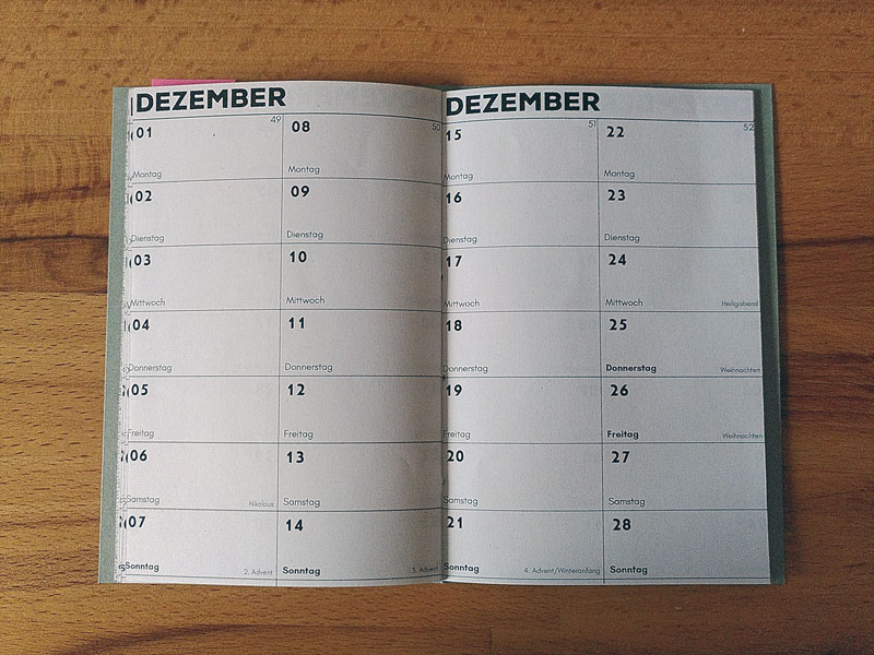 Kalender mit Umschlag aus grüner Pappe, aufgeschlagen ist der Dezember